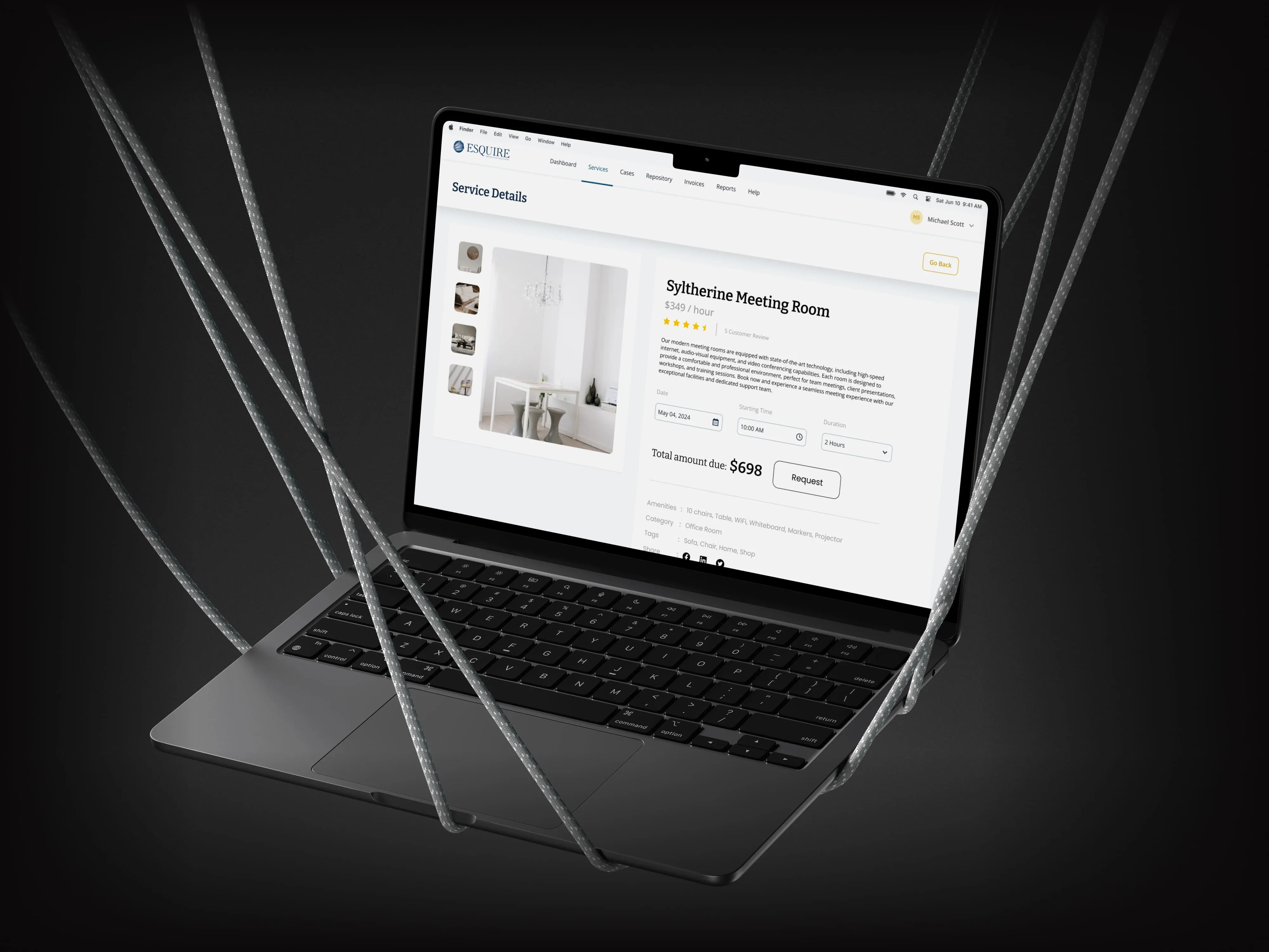 Laptop suspended in dark straps, showing the Esquire meeting room booking page
